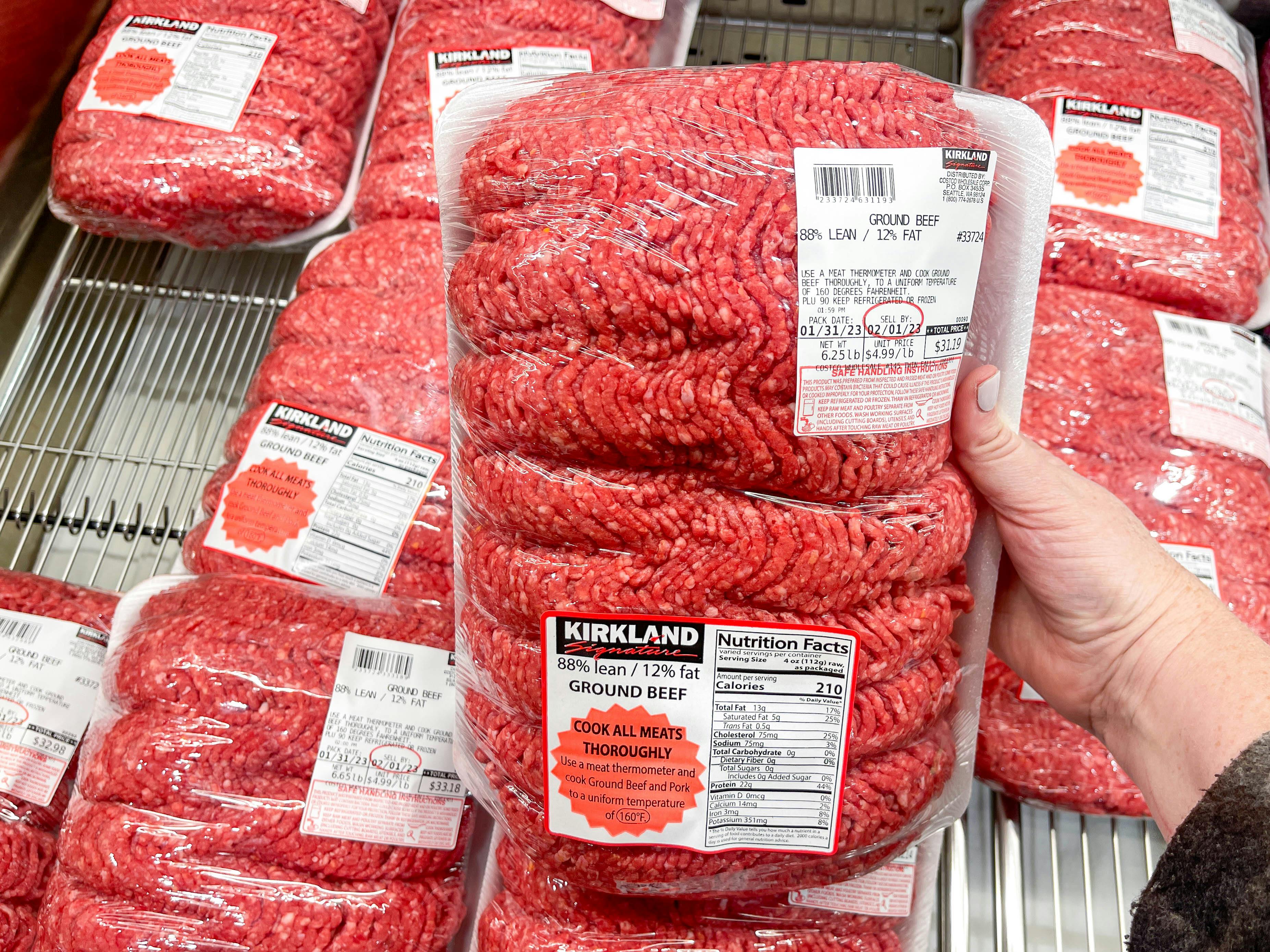 a person holding a large family pack of ground beef 