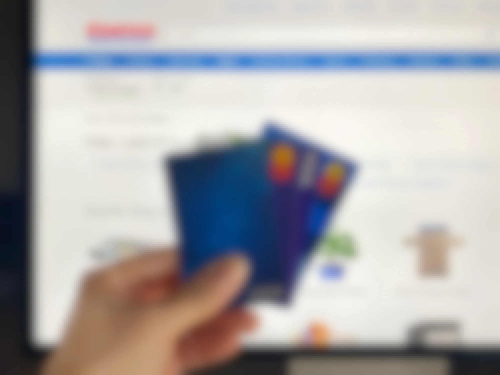person holding visa and mastercard credit cards with costco website in background