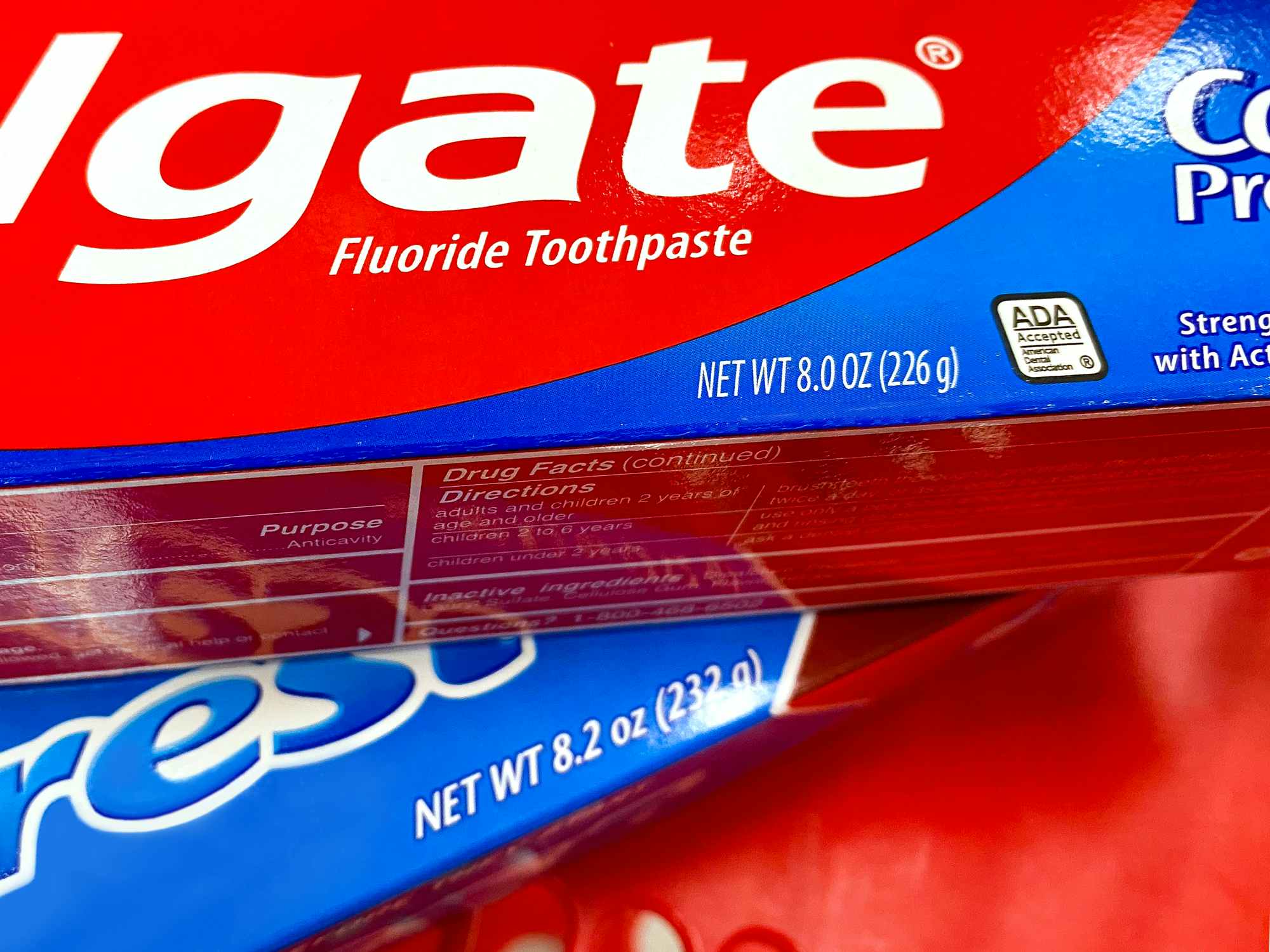 detail of colgate and crest toothpaste boxes with weight