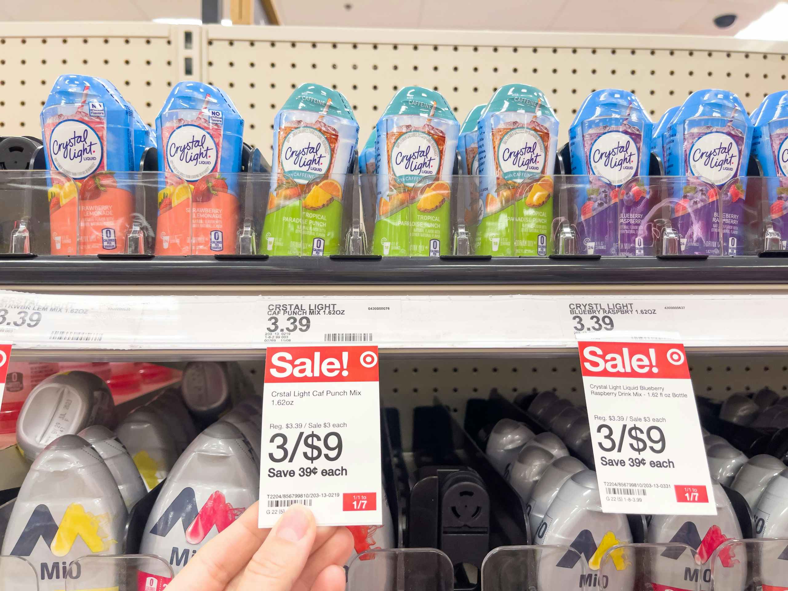 A variety of Crystal Light Liquids sitting on a store shelf with sale signs attached to it.