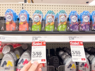 A variety of Crystal Light Liquids sitting on a store shelf with sale signs attached to it.