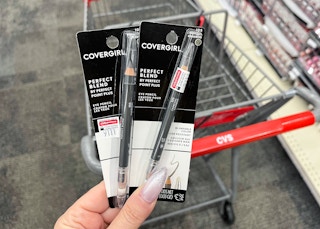 hand holding two packs of Covergirl Perfect Blend Eye Pencils