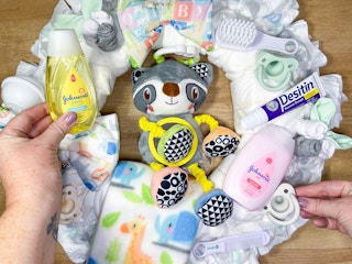 baby items being placed on a diy diaper wreath