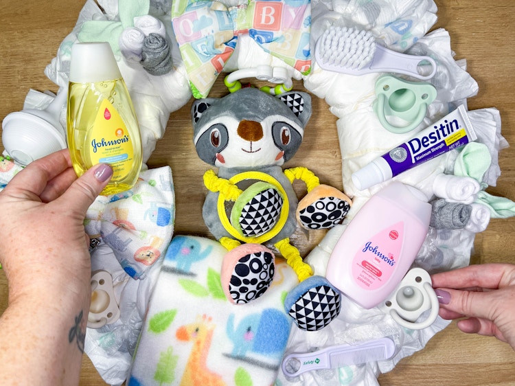 baby items being placed on a diy diaper wreath