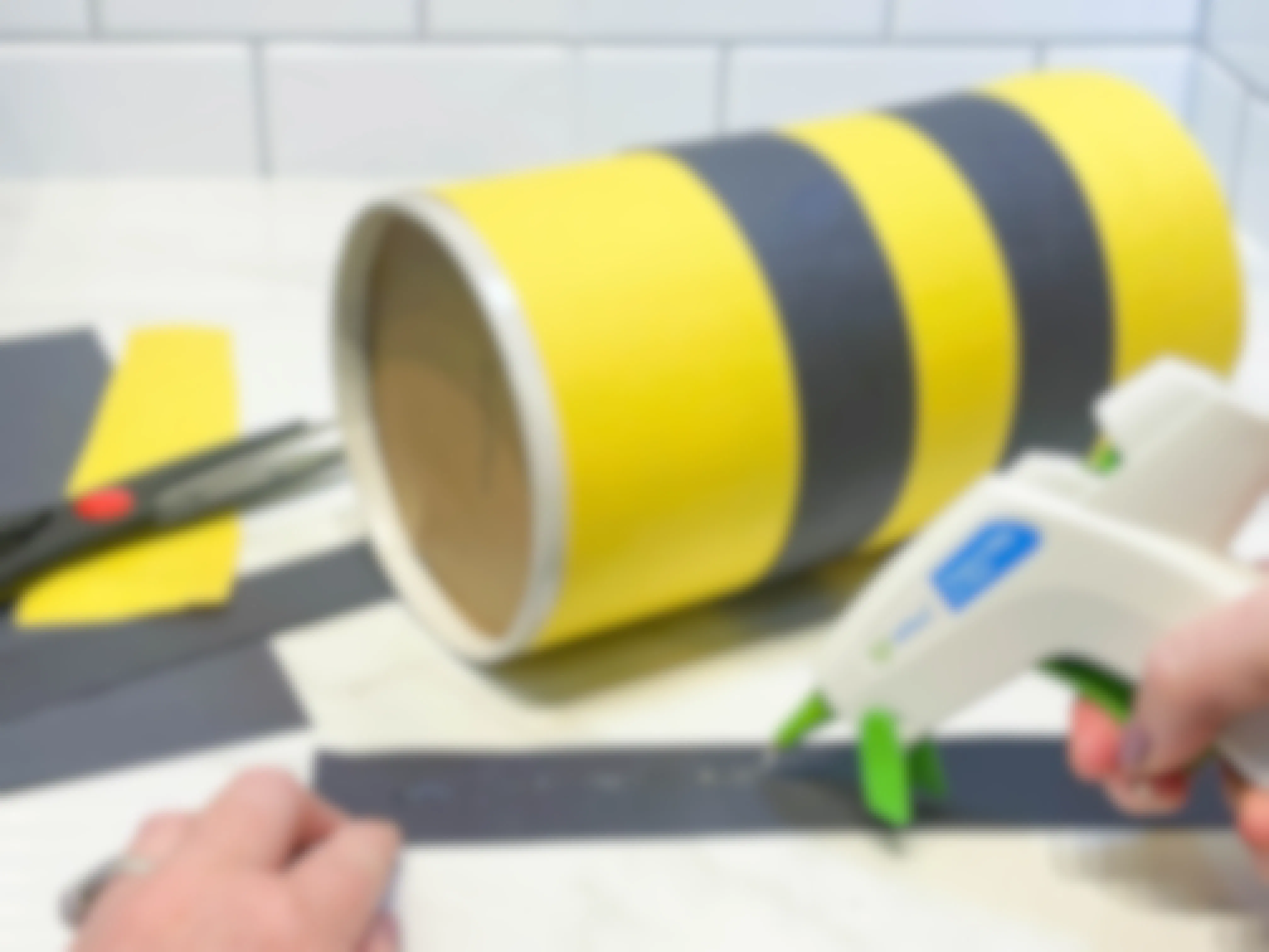 gluing strips of construction paper to a round container 