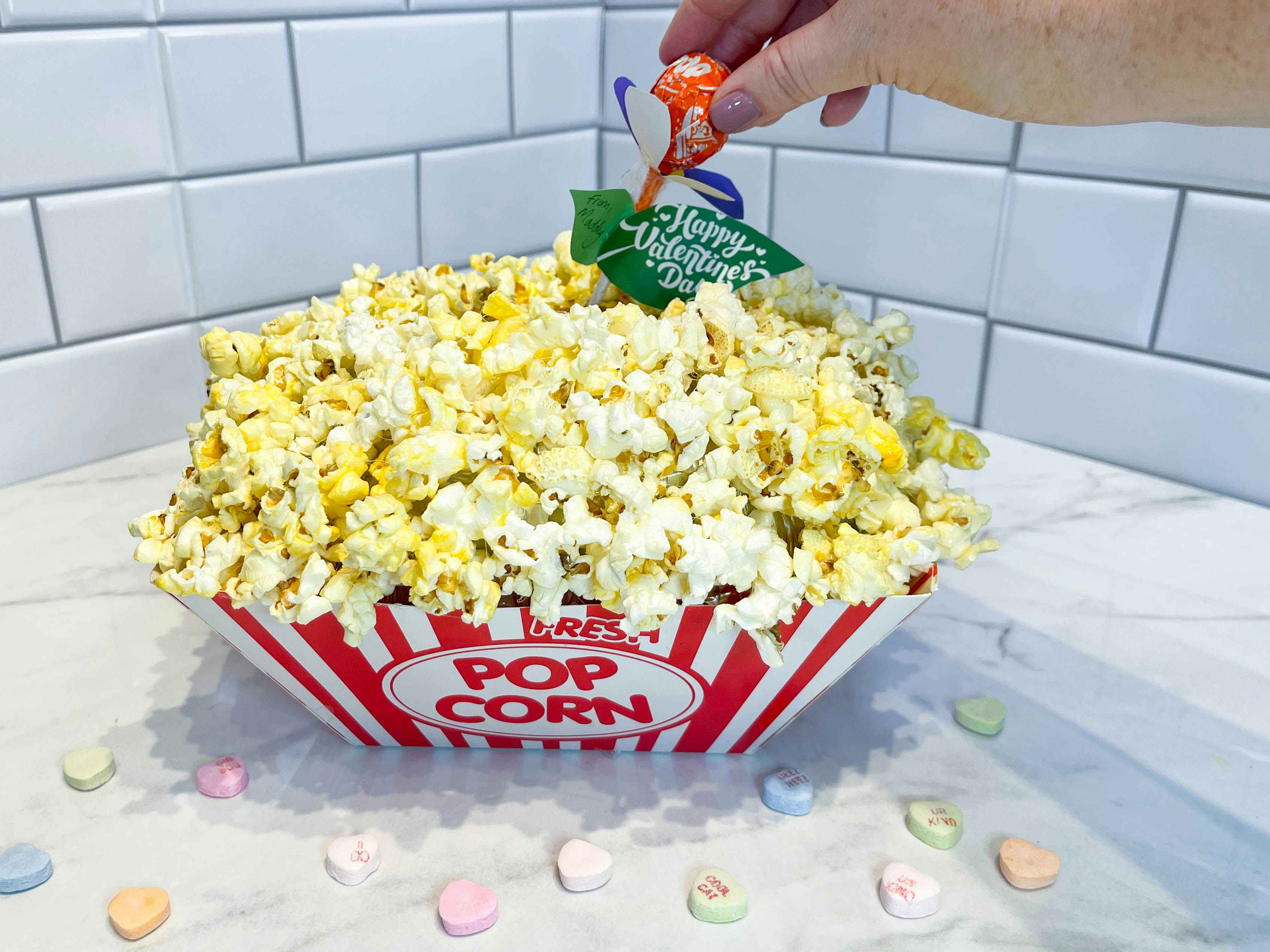 a diy popcorn valentine box with a person putting in a valentine in the back