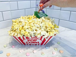 a diy popcorn valentine box with a person putting in a valentine in the back