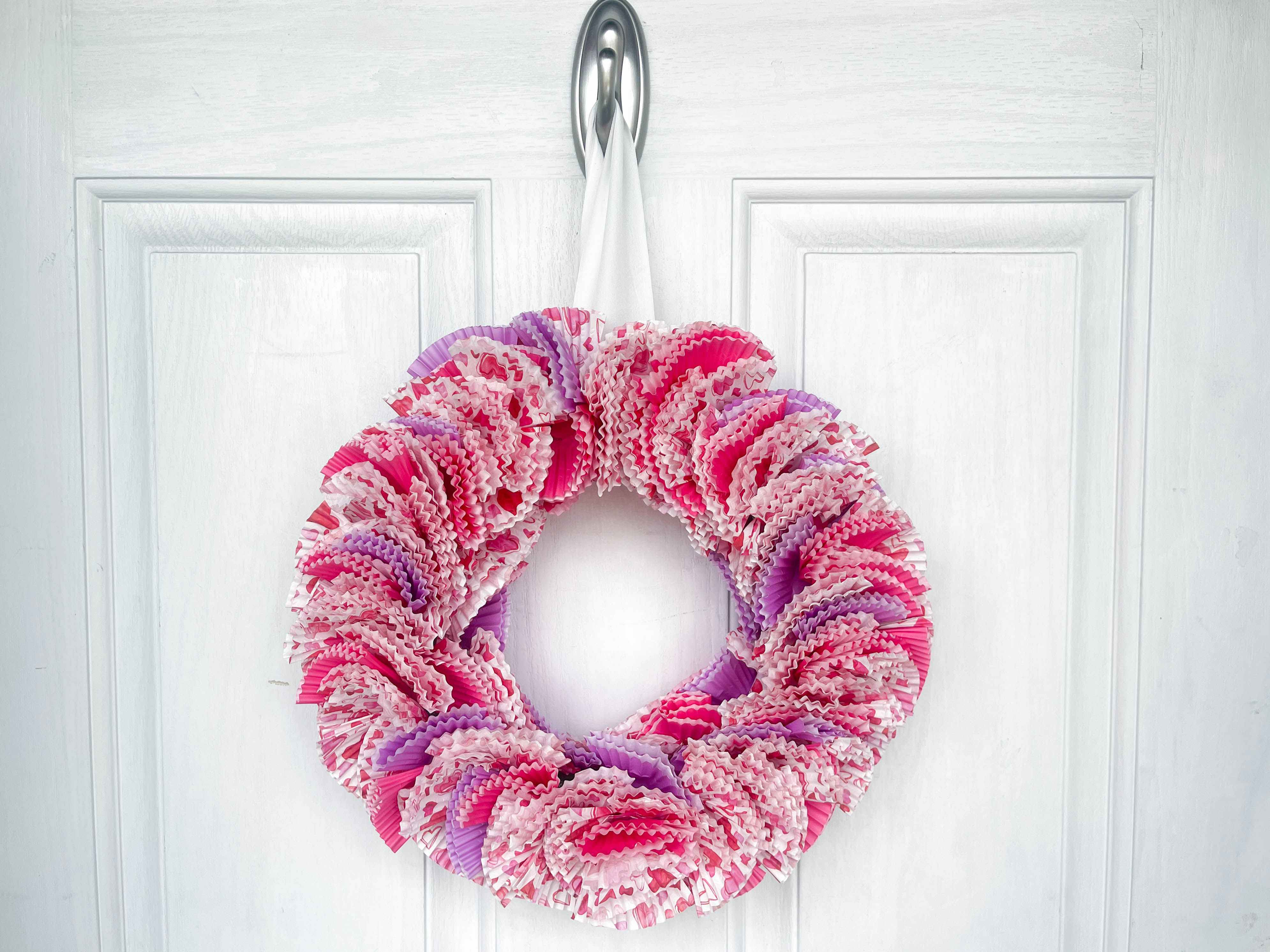 a diy wreath from cupcake liners hanging on a door 