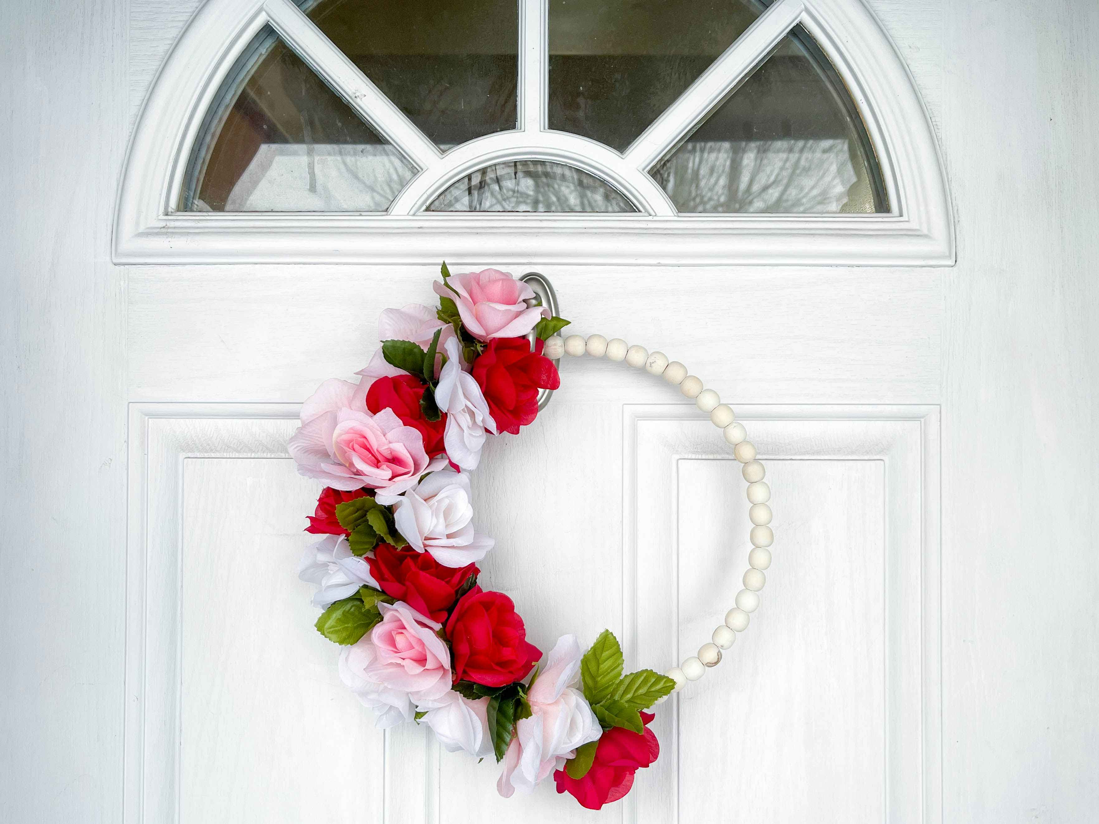 a fake flower and bead wreath hanging on a door