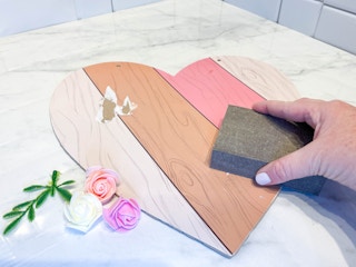 a person sanding a wood heart