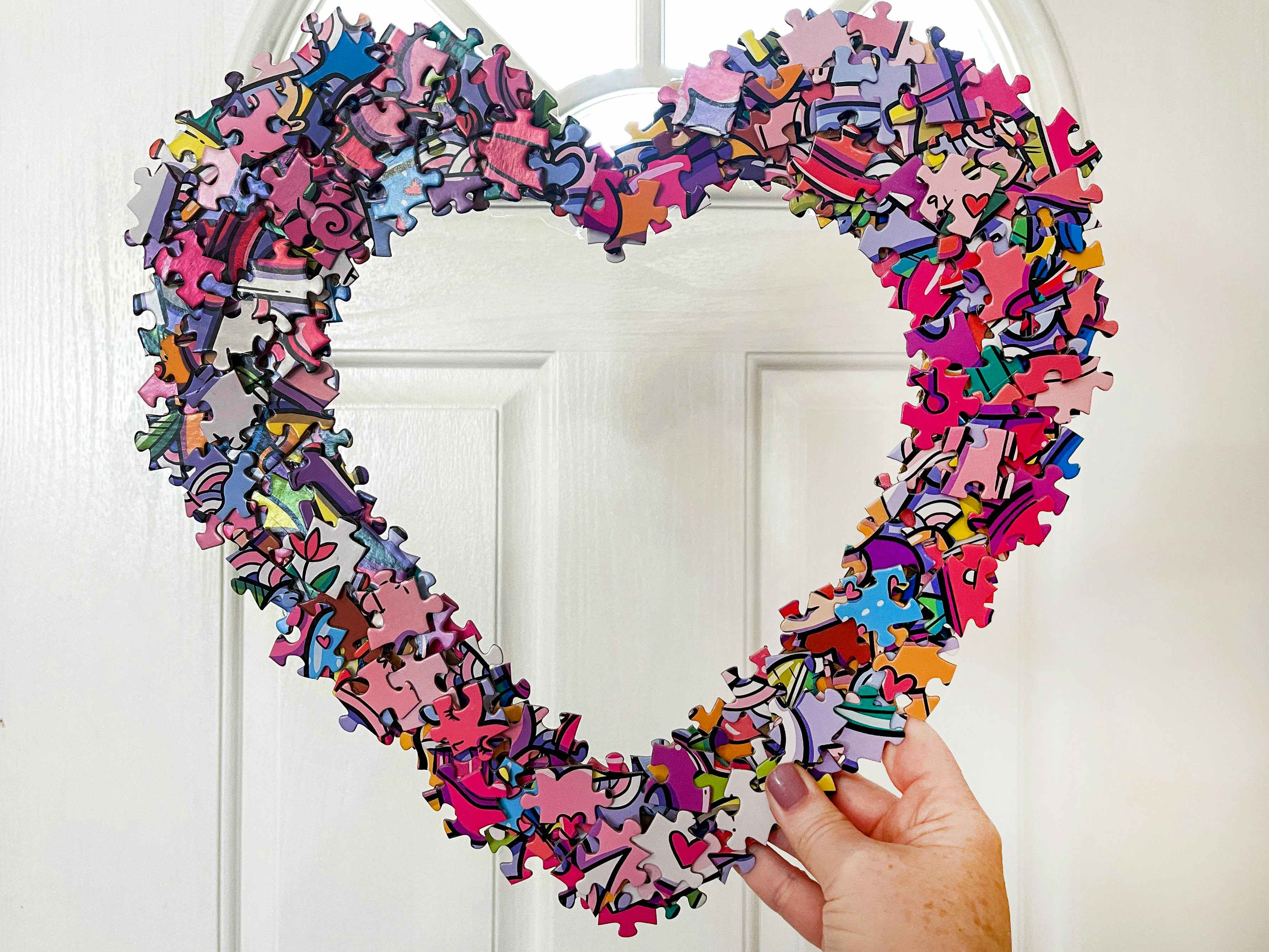 a diy puzzle heart wreath being held