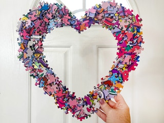 a diy puzzle heart wreath being held