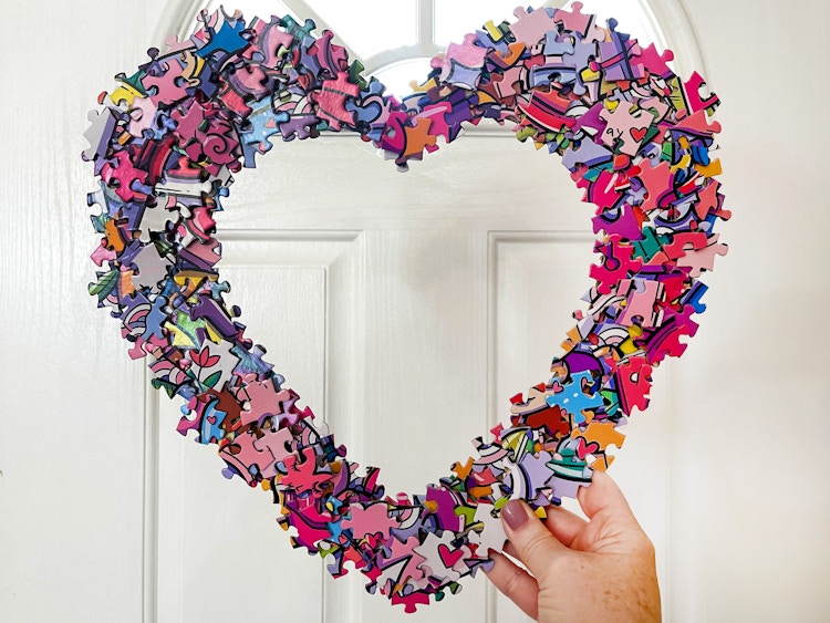 a diy puzzle heart wreath being held