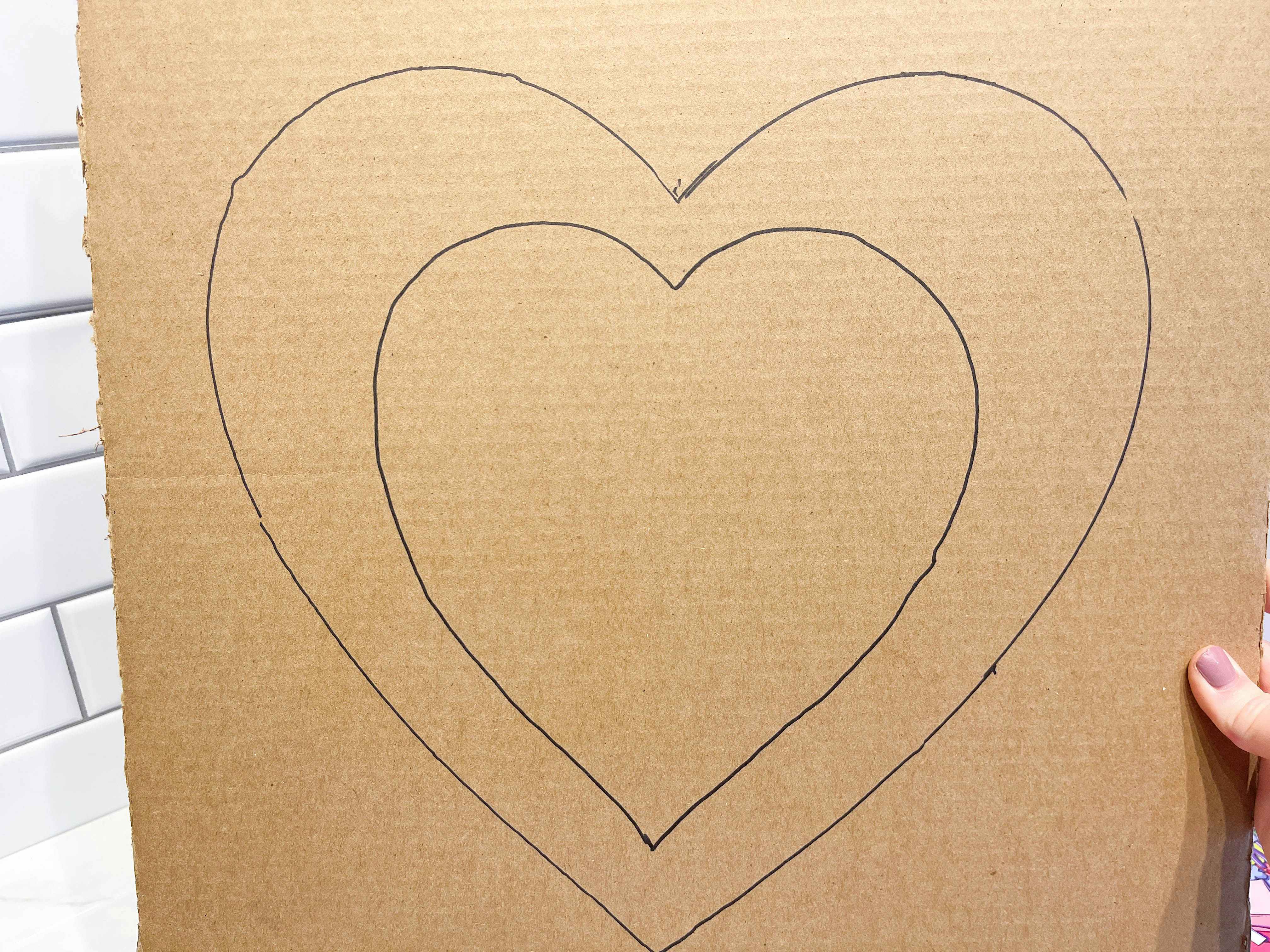 a cardboard sheet with a heart stencil being drawn on it 