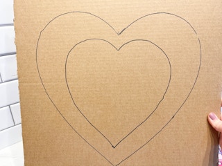 a cardboard sheet with a heart stencil being drawn on it