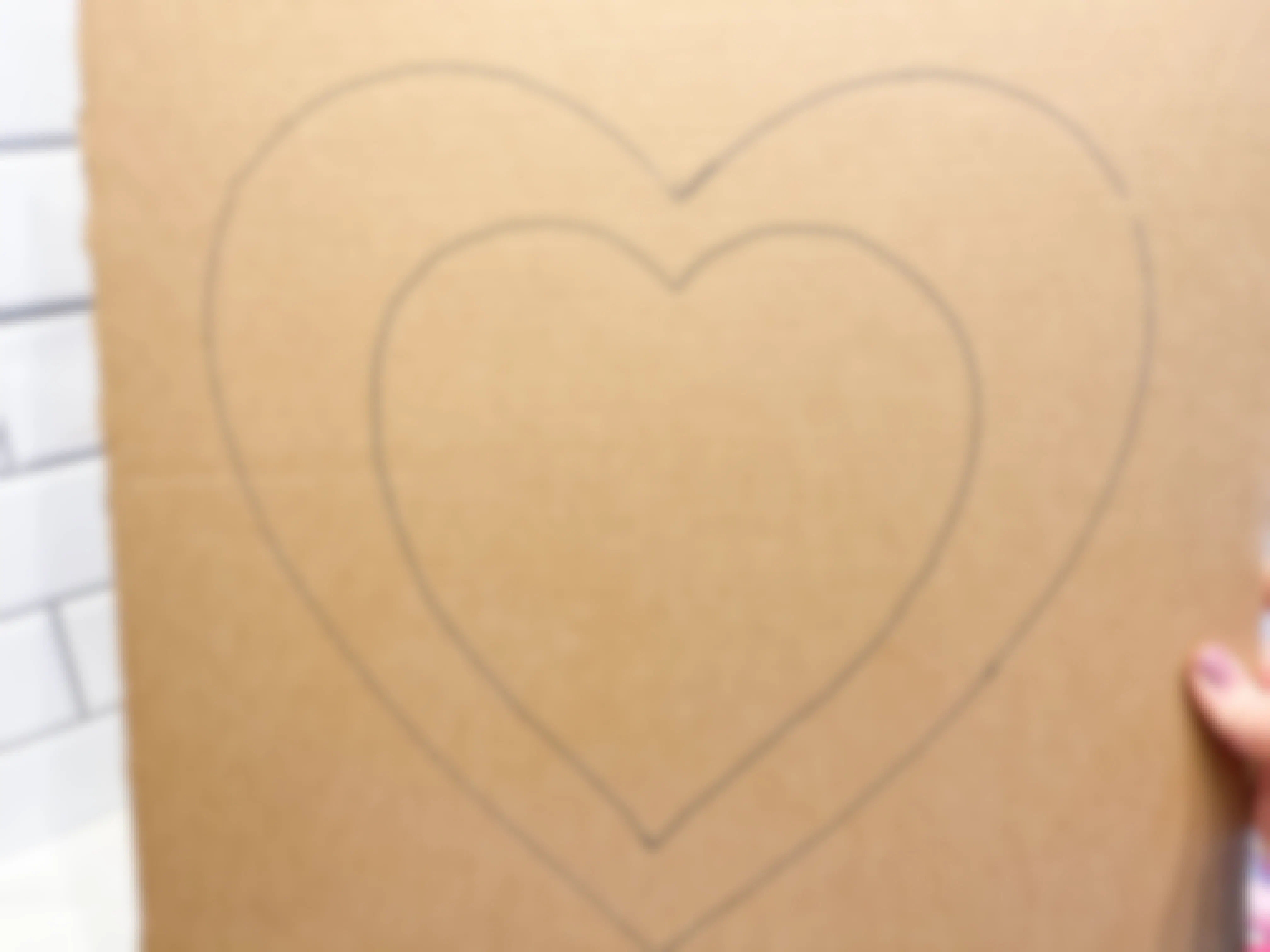 a cardboard sheet with a heart stencil being drawn on it 