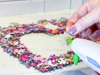 a puzzle piece being glued on a heart wreath