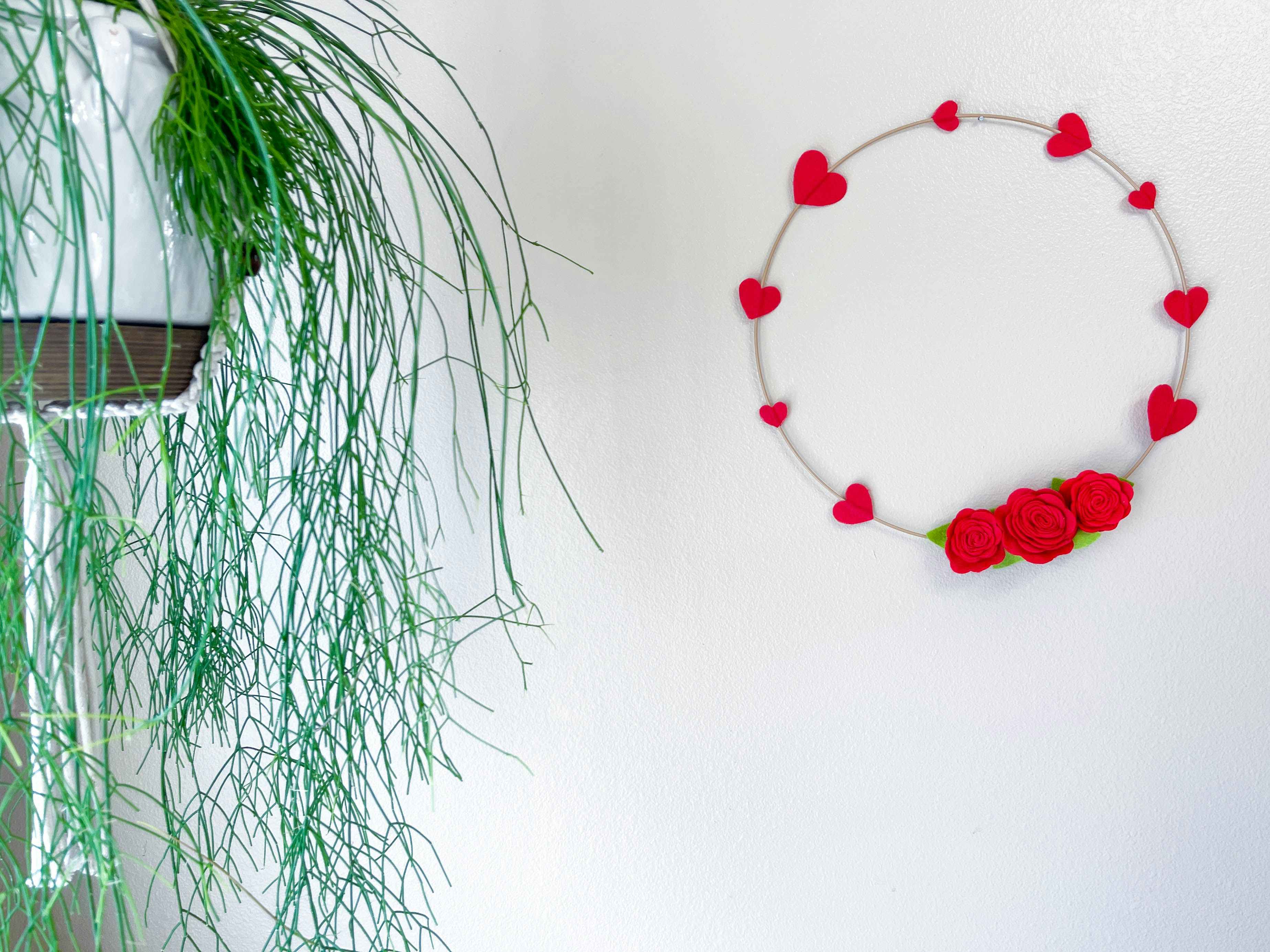 a felt rose and heart wreath hanging on a wall