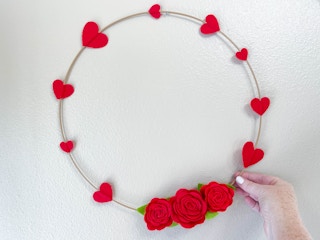 a felt rose and heart wreath hanging on a wall