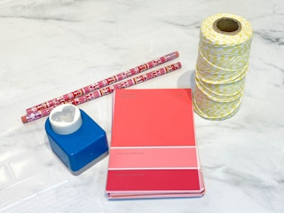 paint swatches, pencils, heart paper punch, and twine on a counter