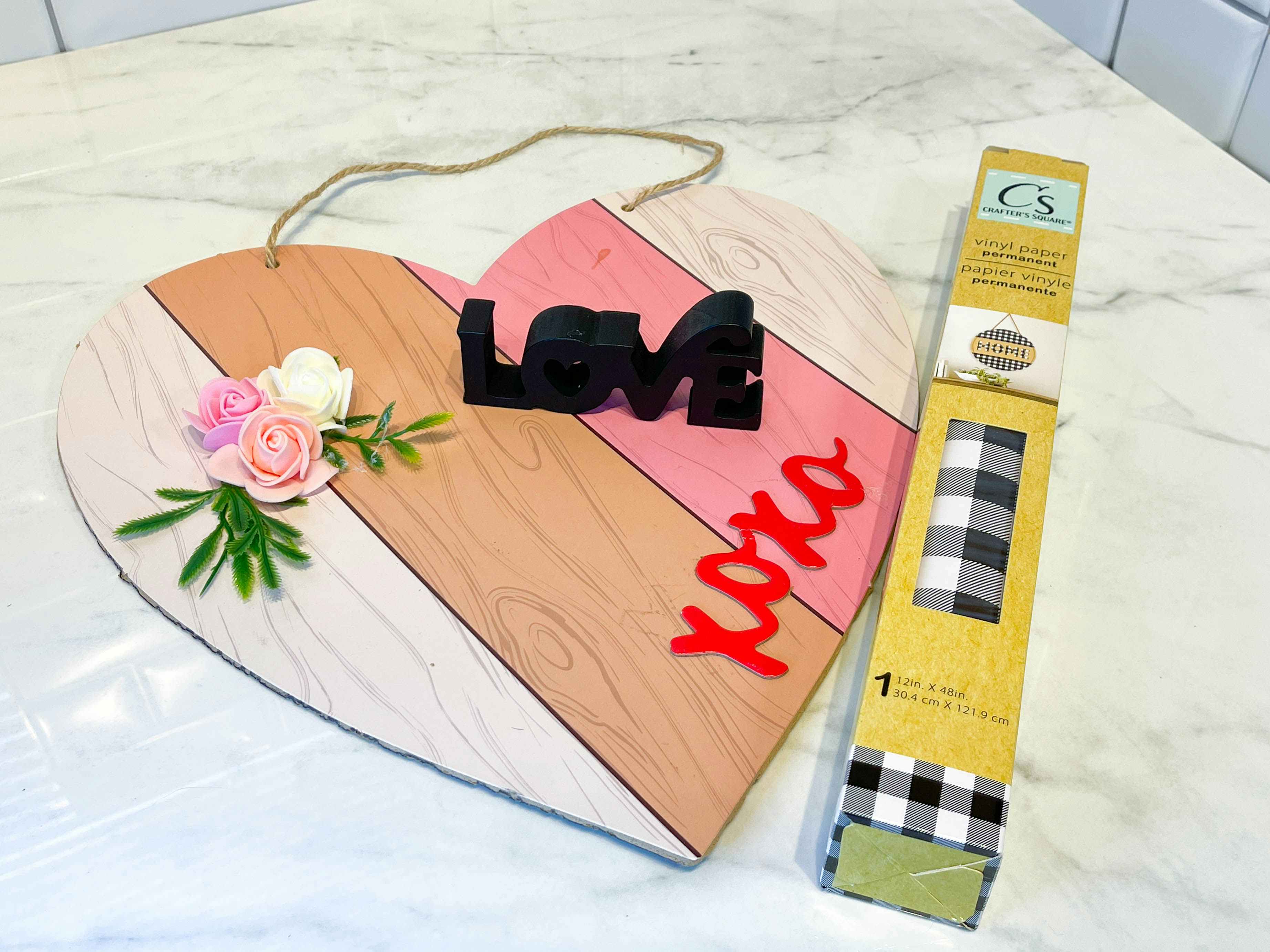 a wood heart decor with a roll of paper vinyl on a counter 