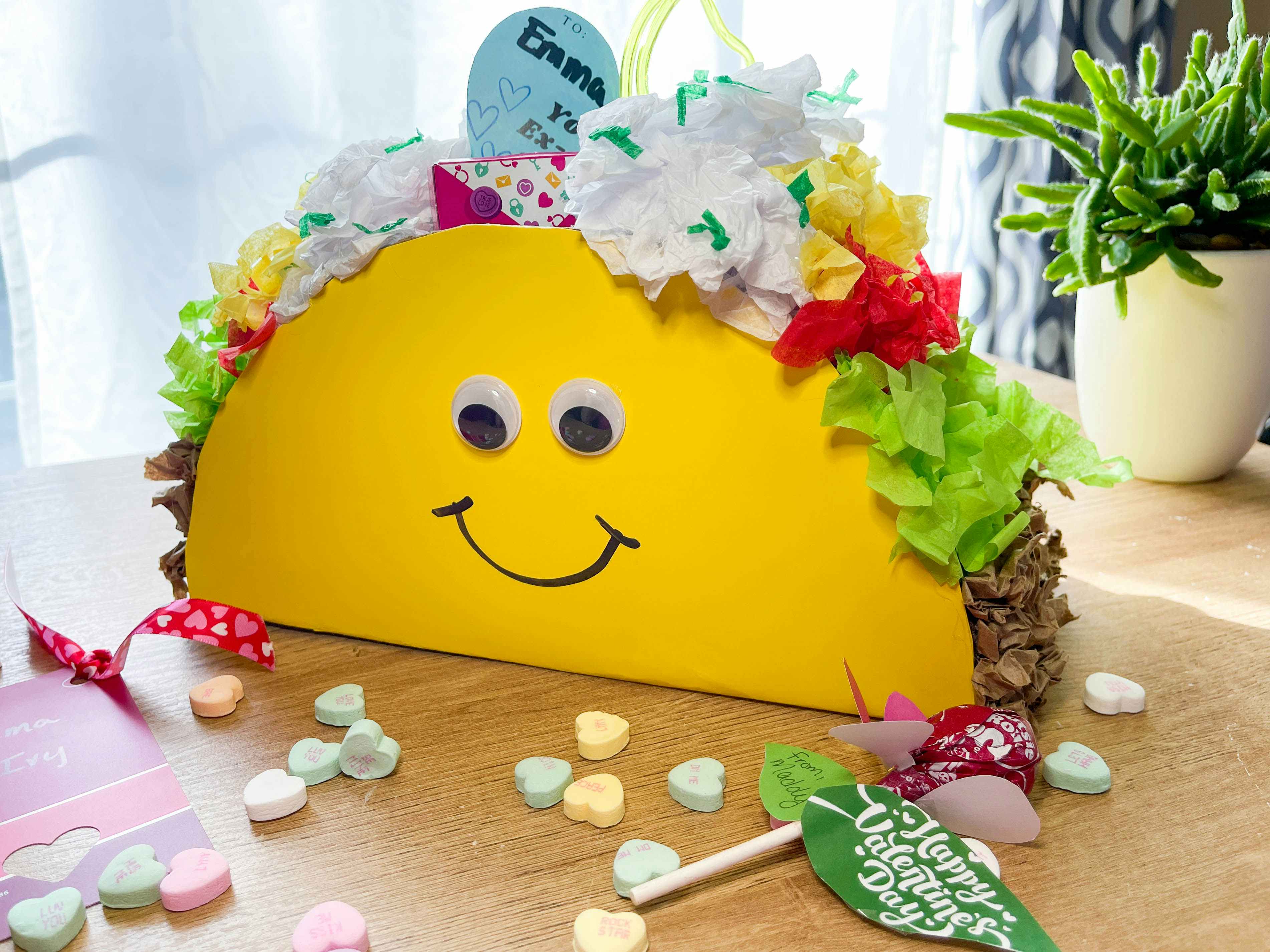 Diy taco valentines day box made from tissue paper and poster board sitting on a table