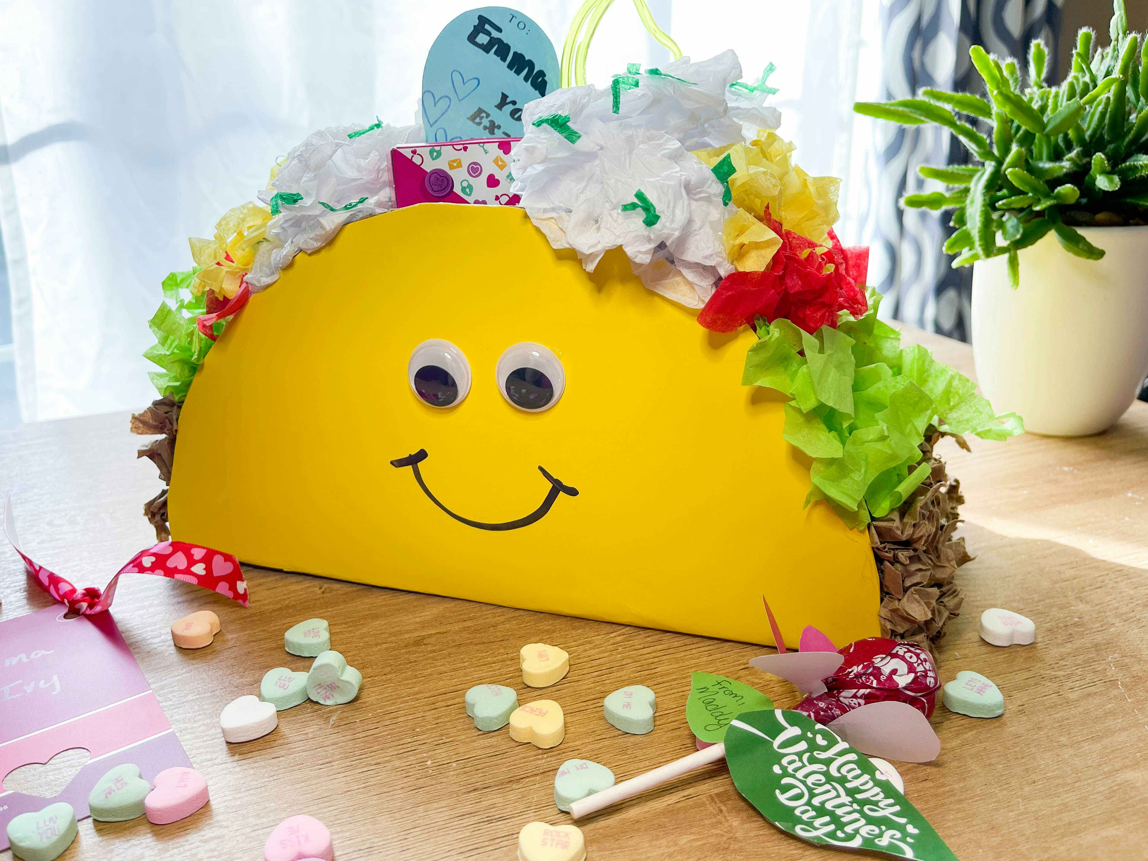 Diy taco valentines day box made from tissue paper and poster board sitting on a table 