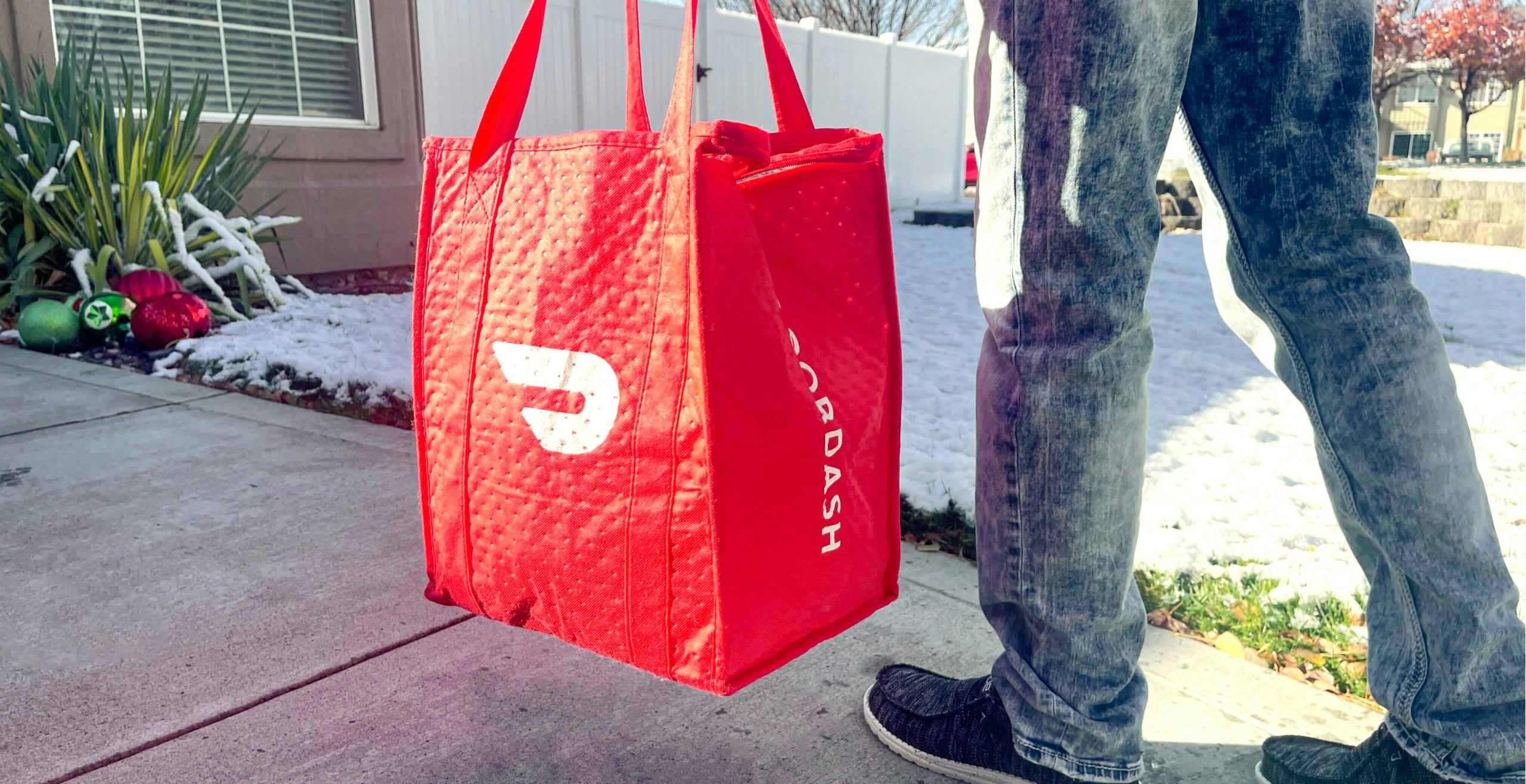 person walking while holding Doordash food delivery bag