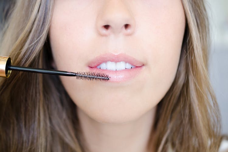 person using mascara wand to exfoliate dry lips
