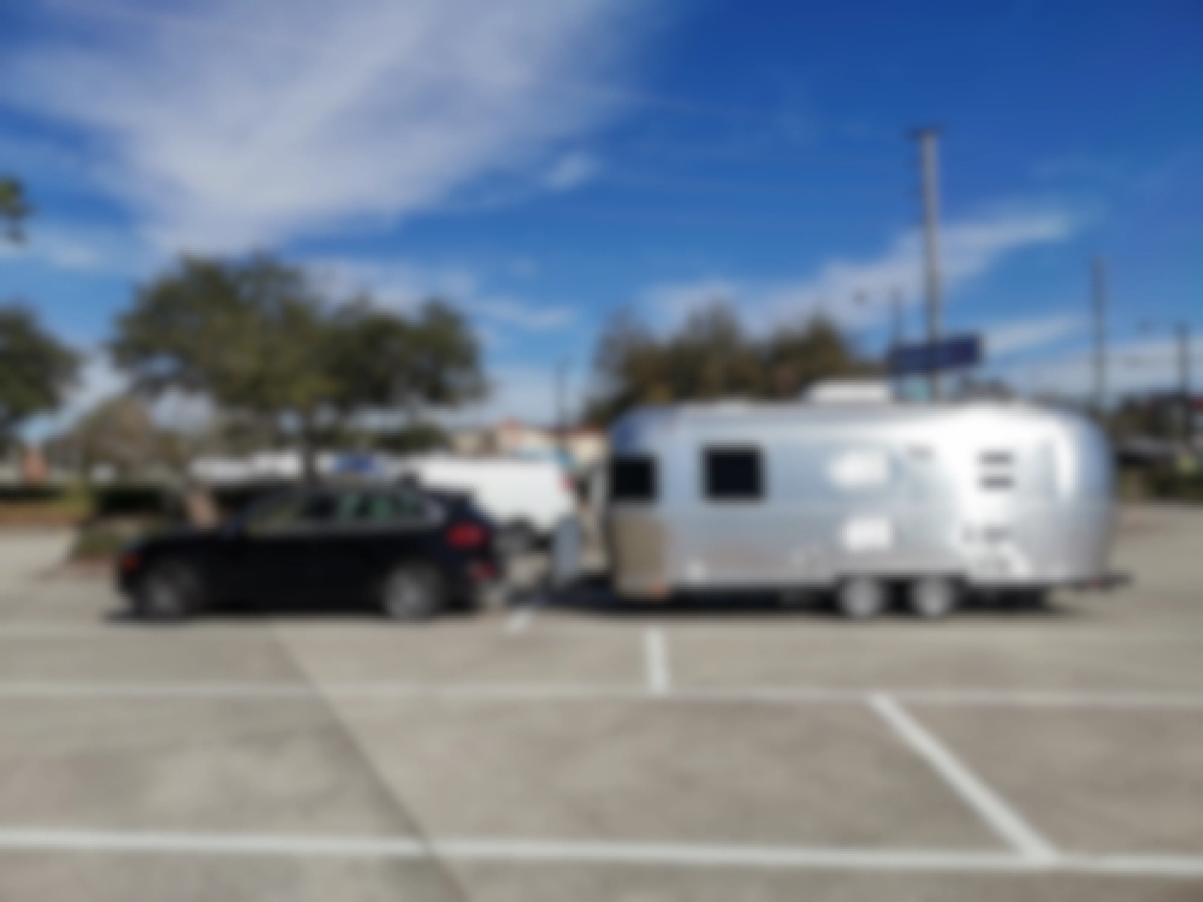 A truck towing an airstream RV parked in a Walmart parking lot