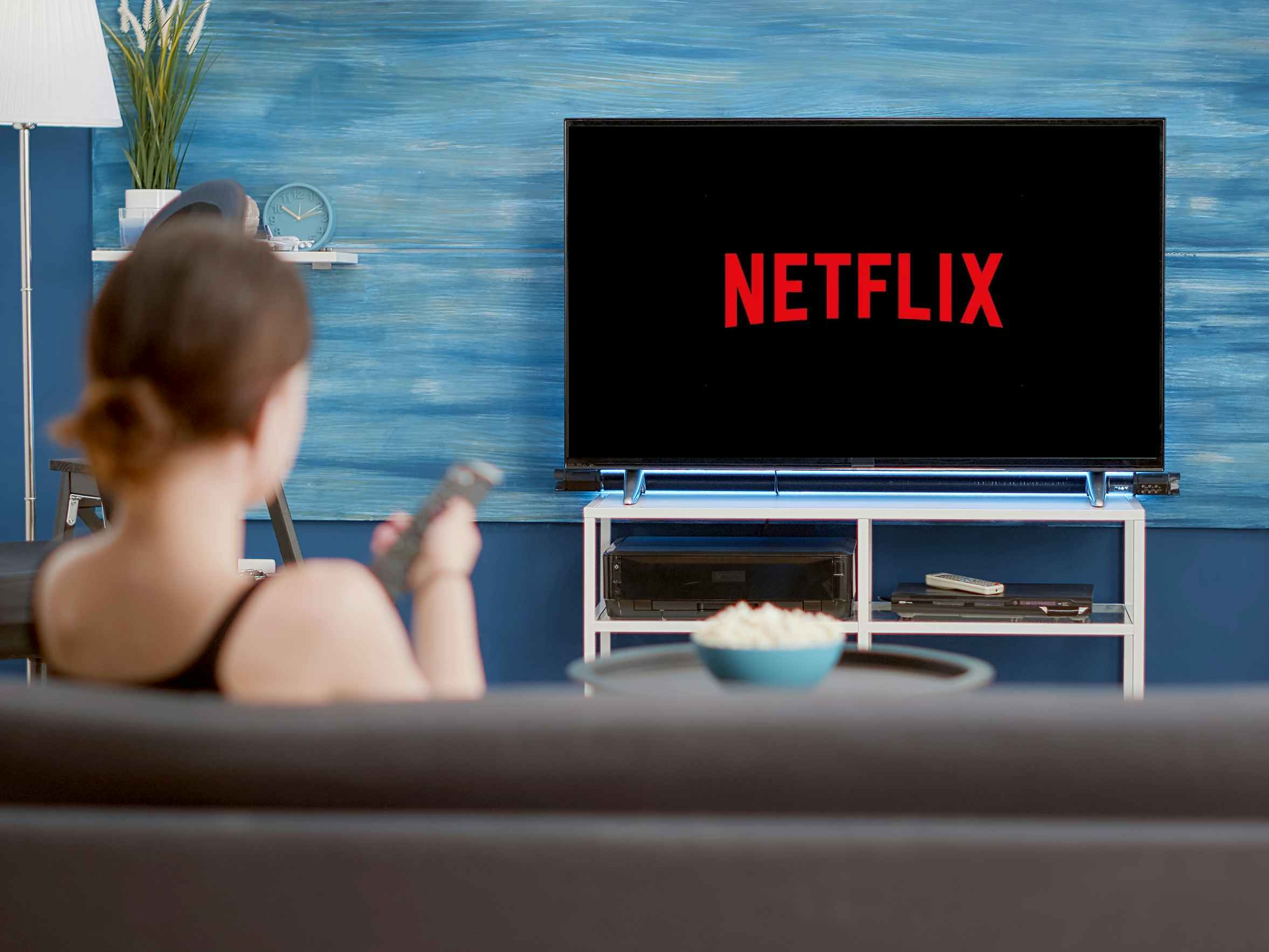 person pointing remote at tv with netflix launching on screen