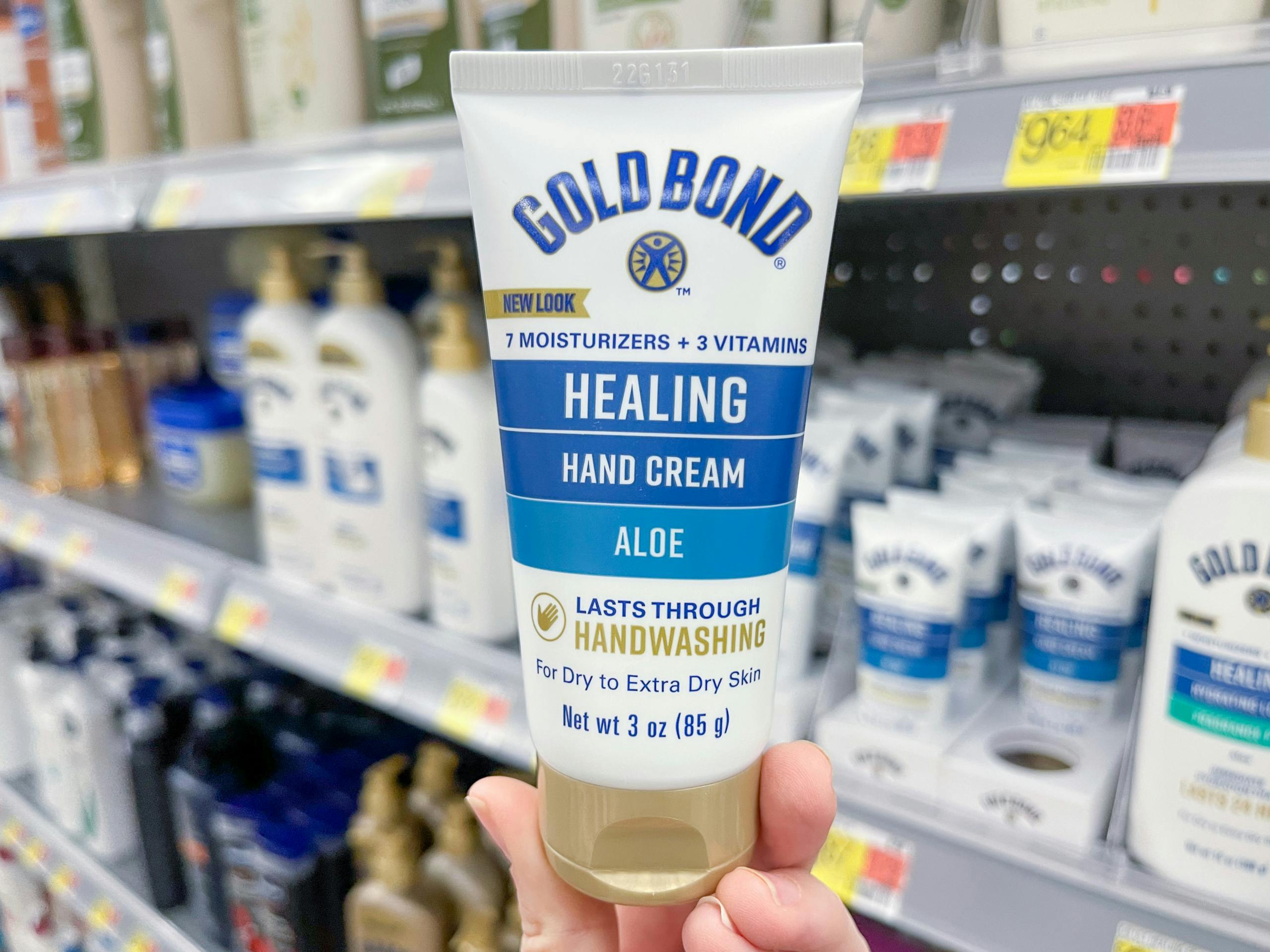 Gold Bond Healing Hand Cream held out in front of a shelf full of other lotions.