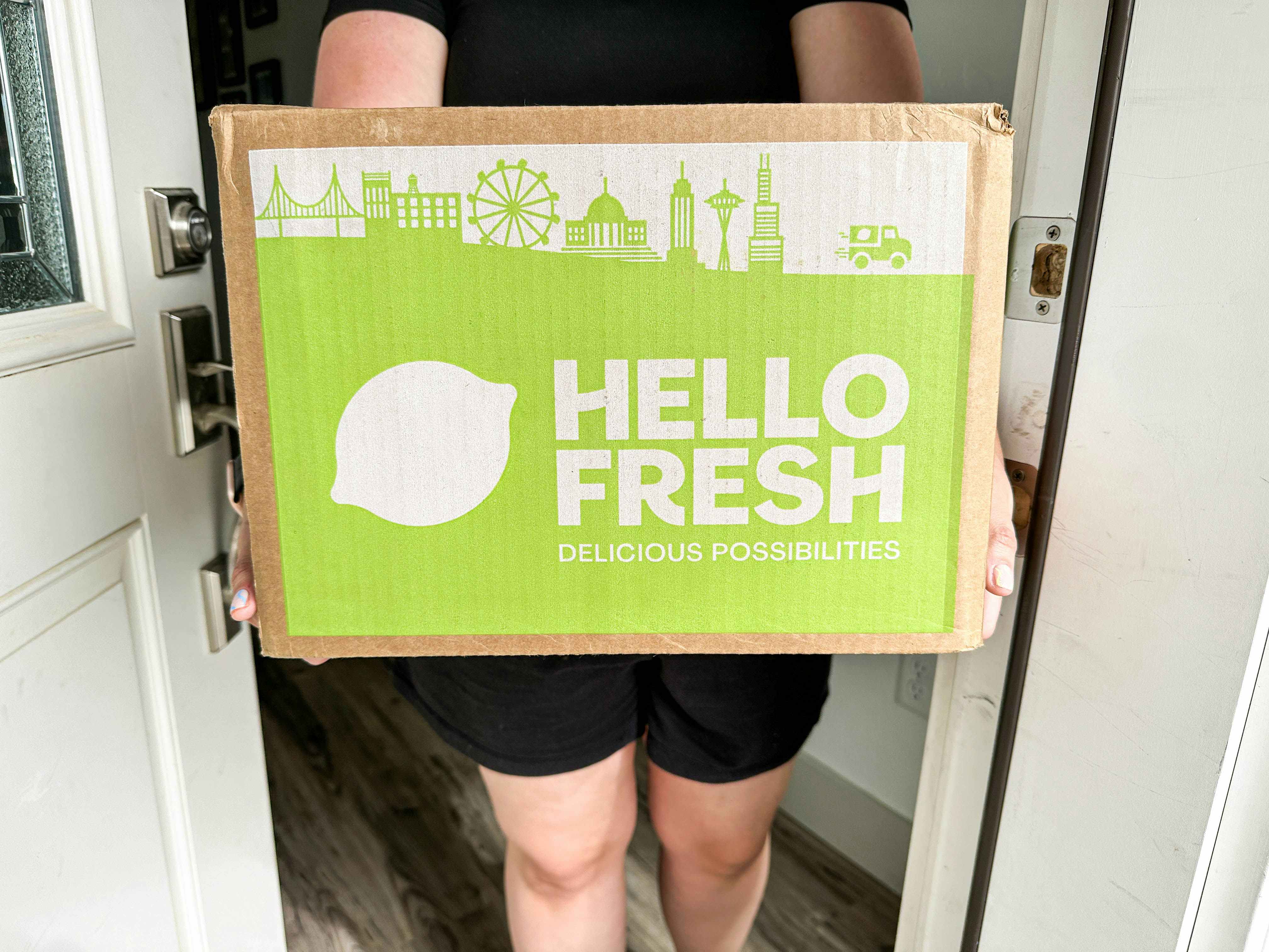a person holding a hello fresh box in doorway