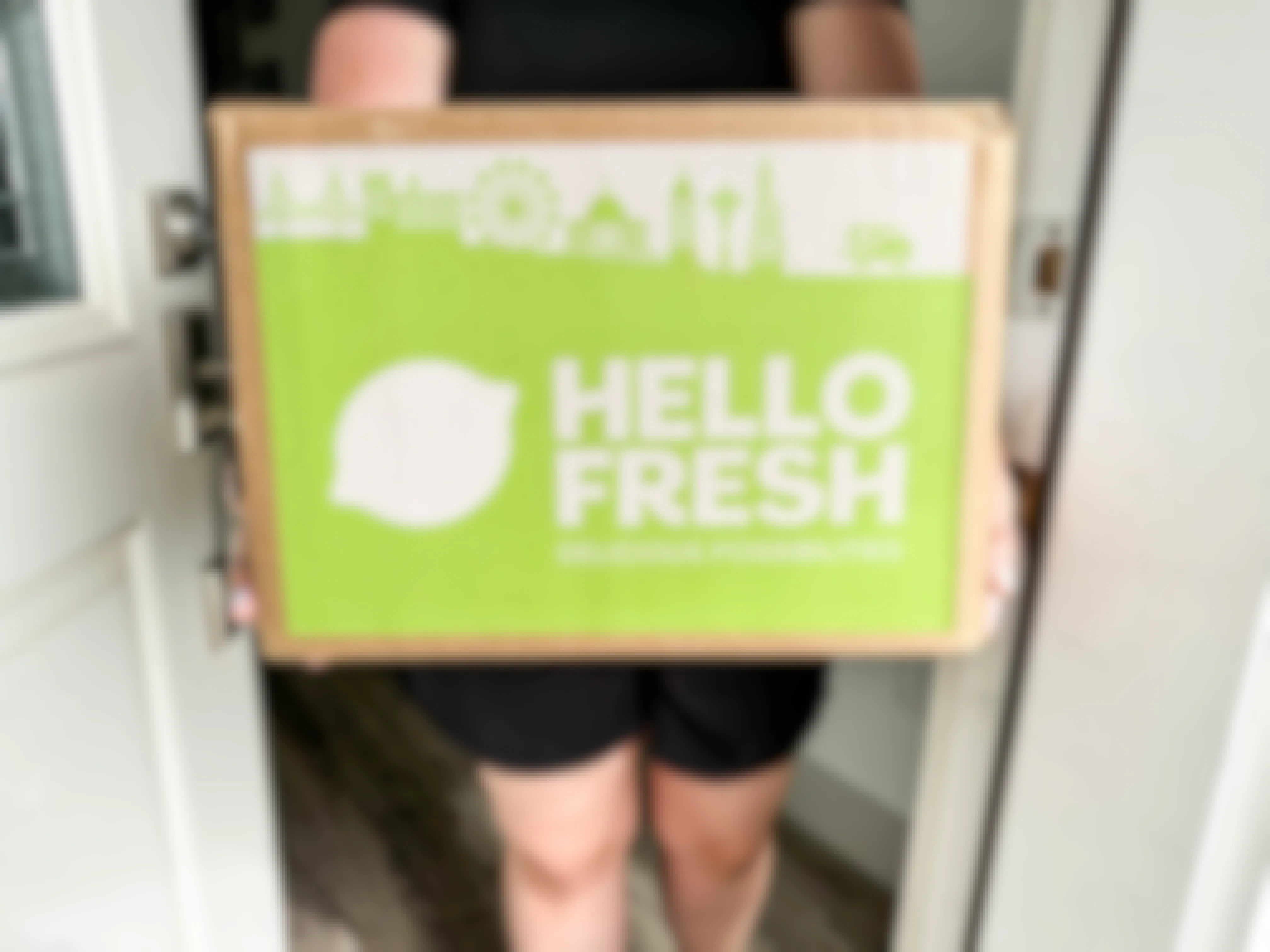 a person holding a hello fresh box in doorway