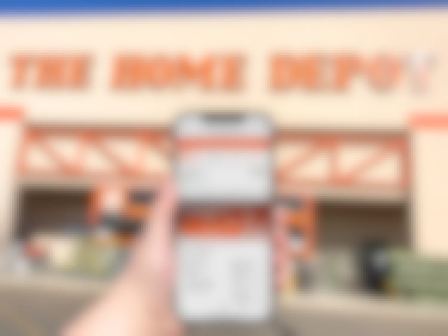 person in front of home depot store holding phone with website