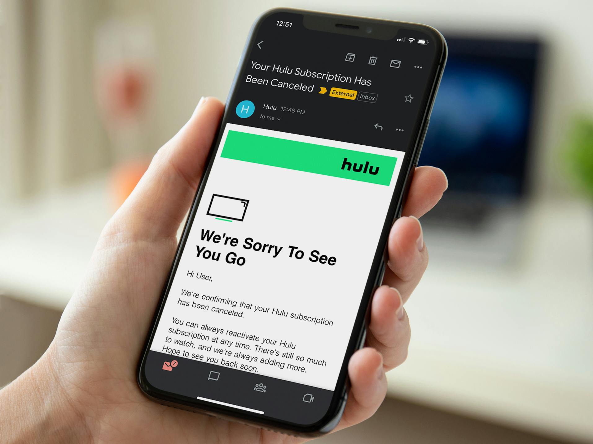 Someone holding a cell phone displaying their confirmation email about canceling their Hulu subscription