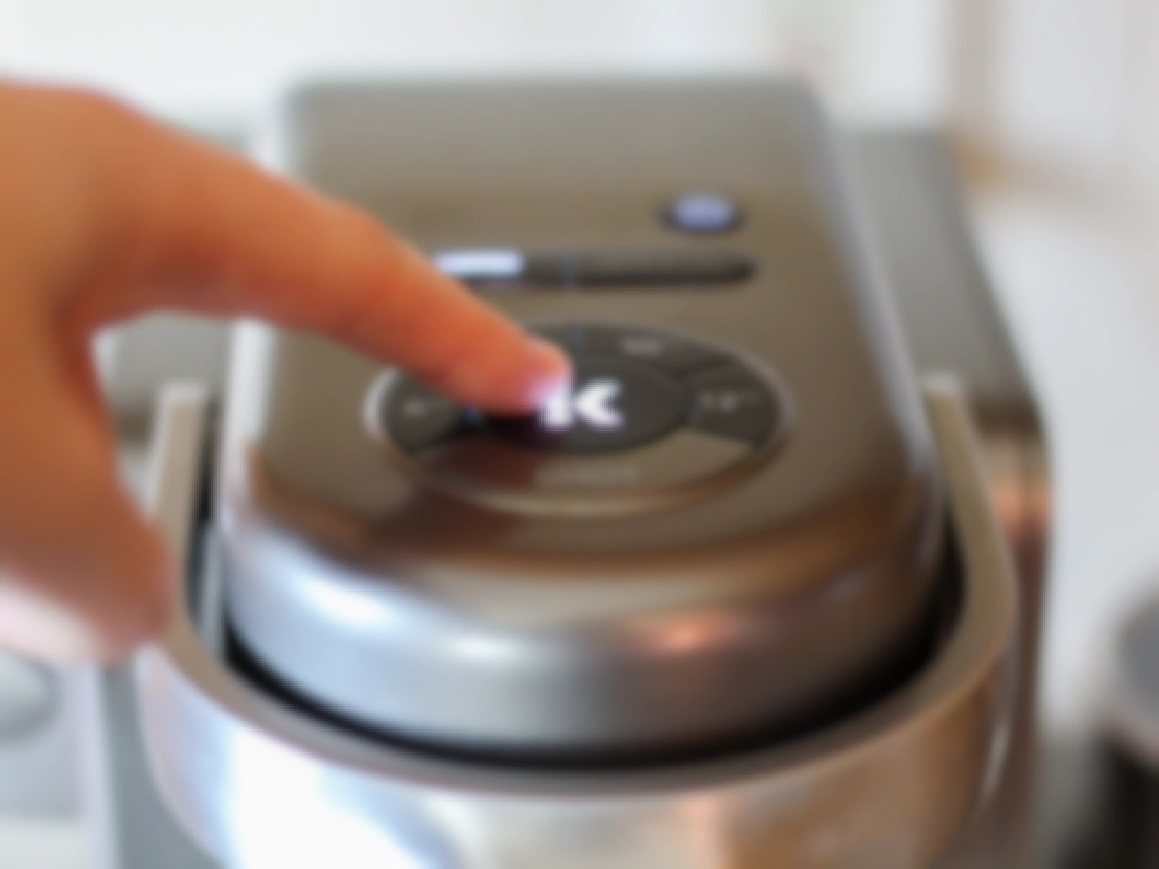person pressing the brew button on a keurig