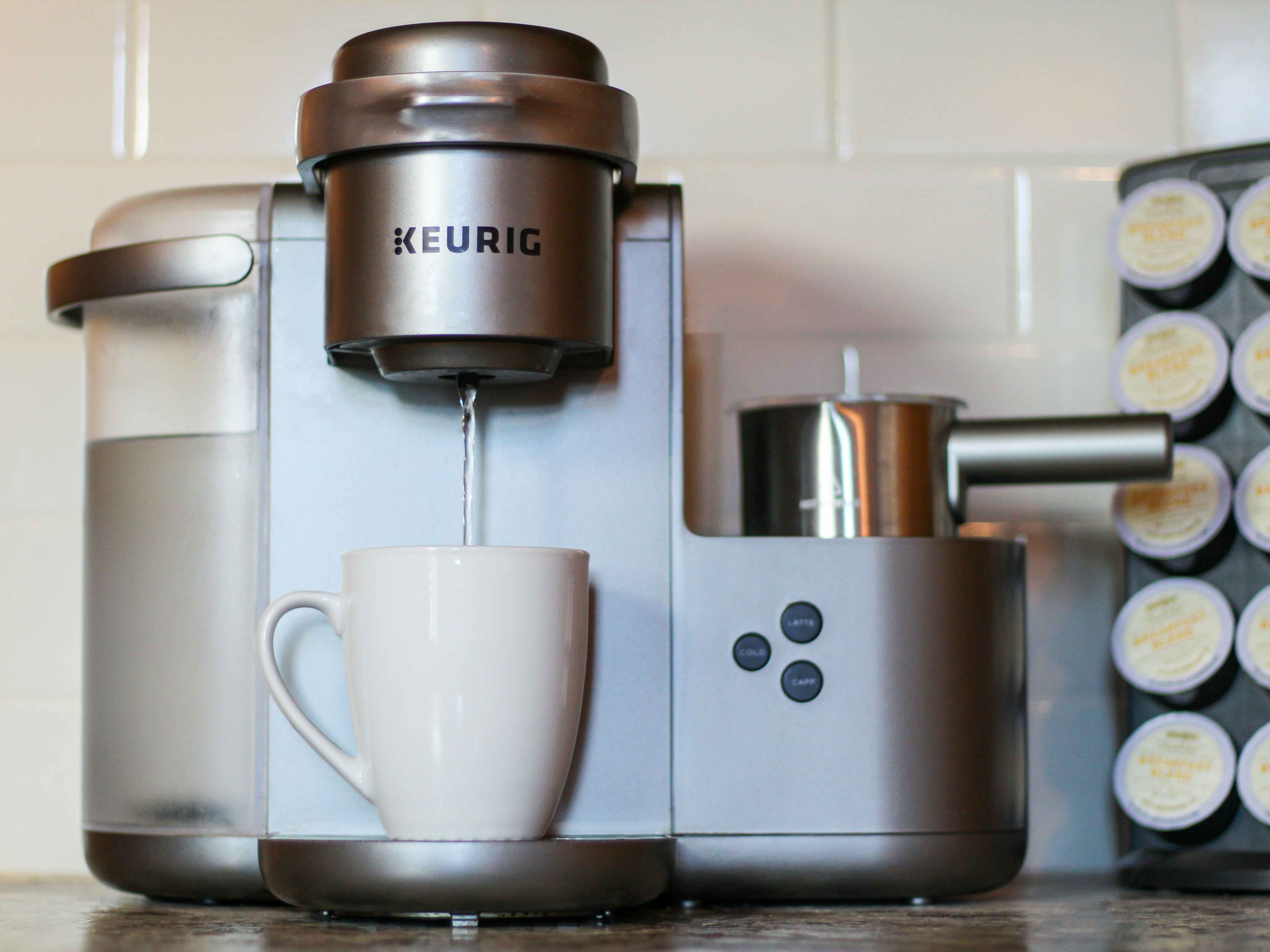 keurig machine running the descale solution through it into a white cup