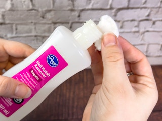 Someone putting some nail polish remover onto a cotton ball
