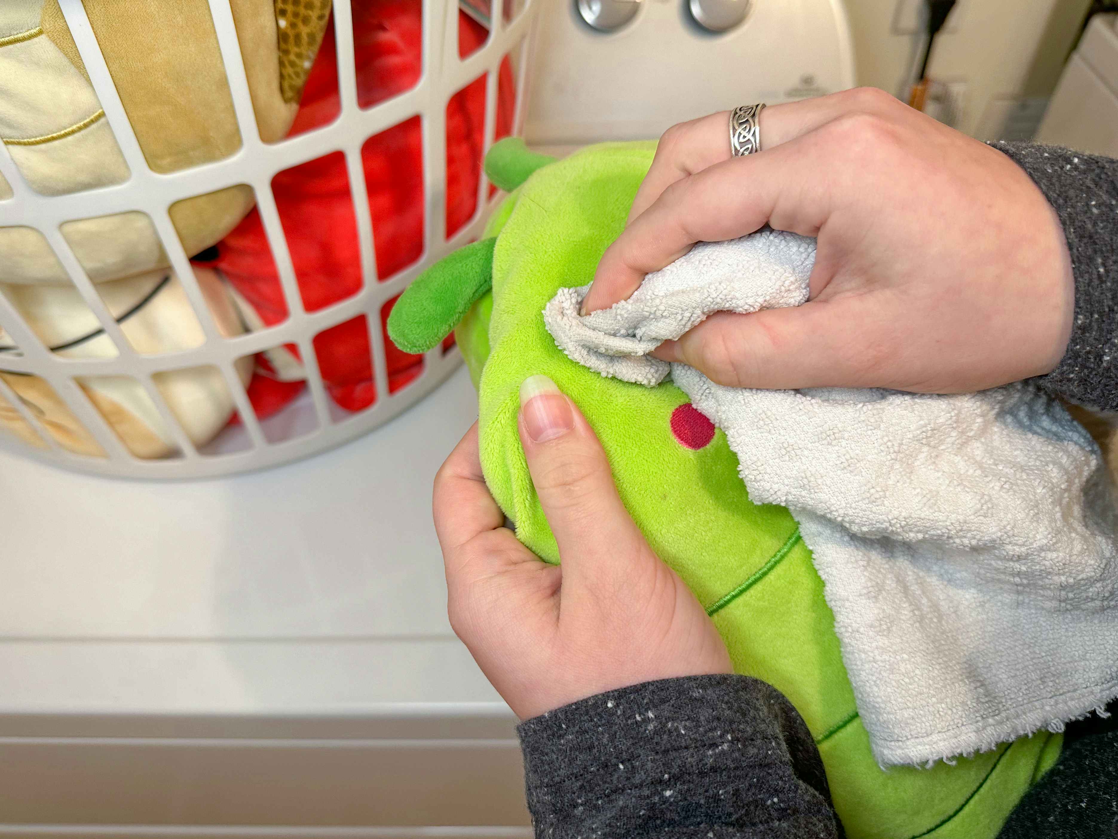 Someone dabbing a cloth on a Squishmallow in the laundry room