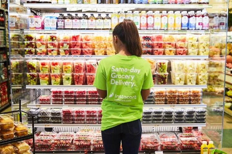 Instacart shopper inside a grocery store looking at pre-cut fruit
