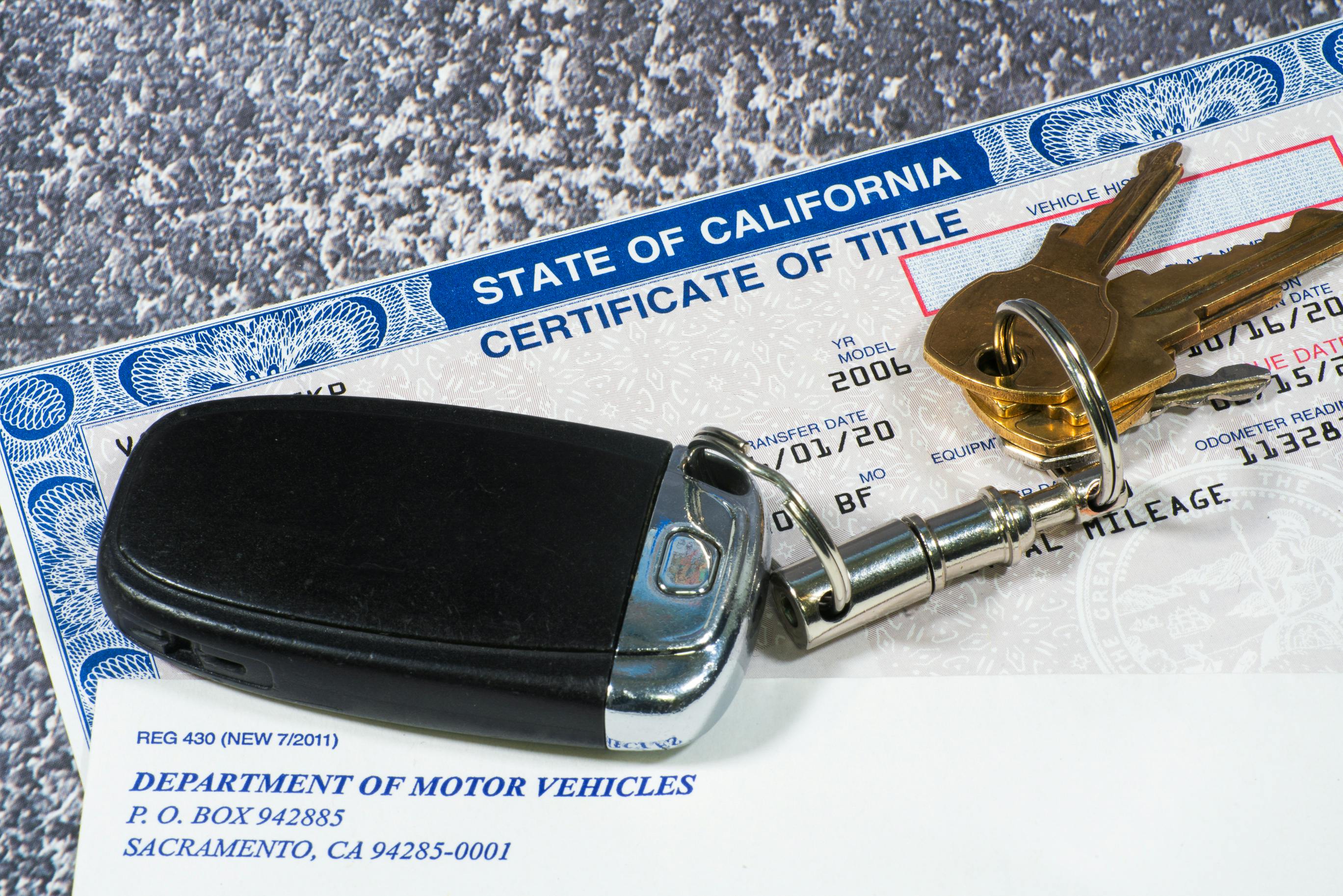 Keys to a vehicle on top of the Certificate of Title from the CA DMV