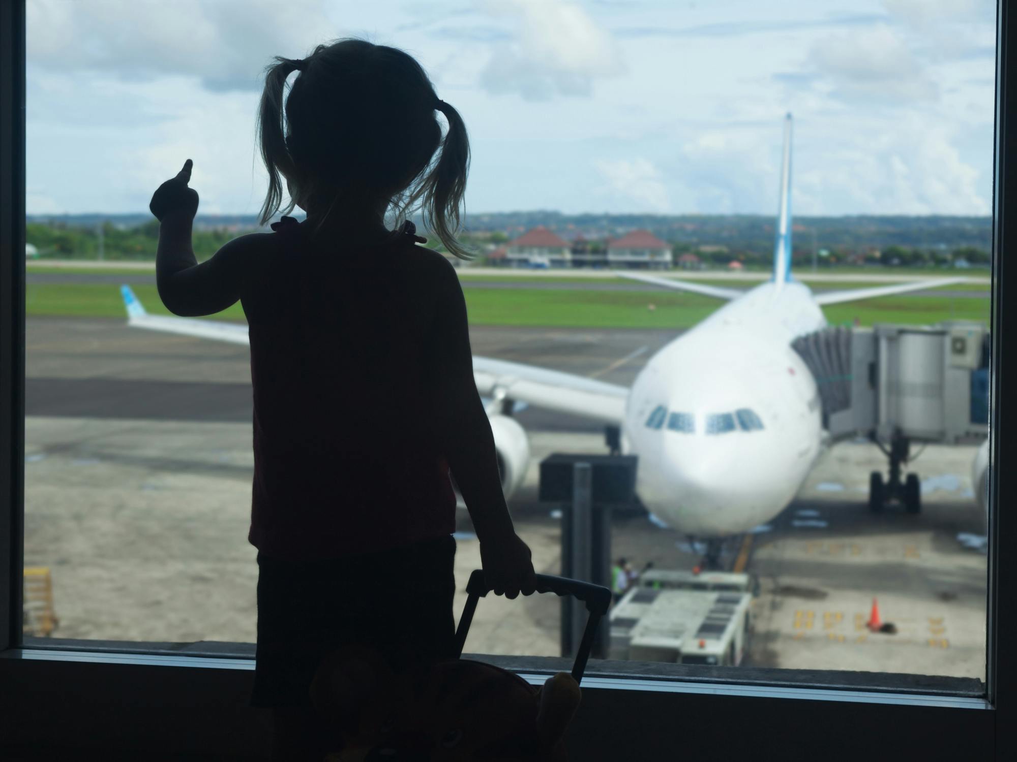 child looking at airplane through a window