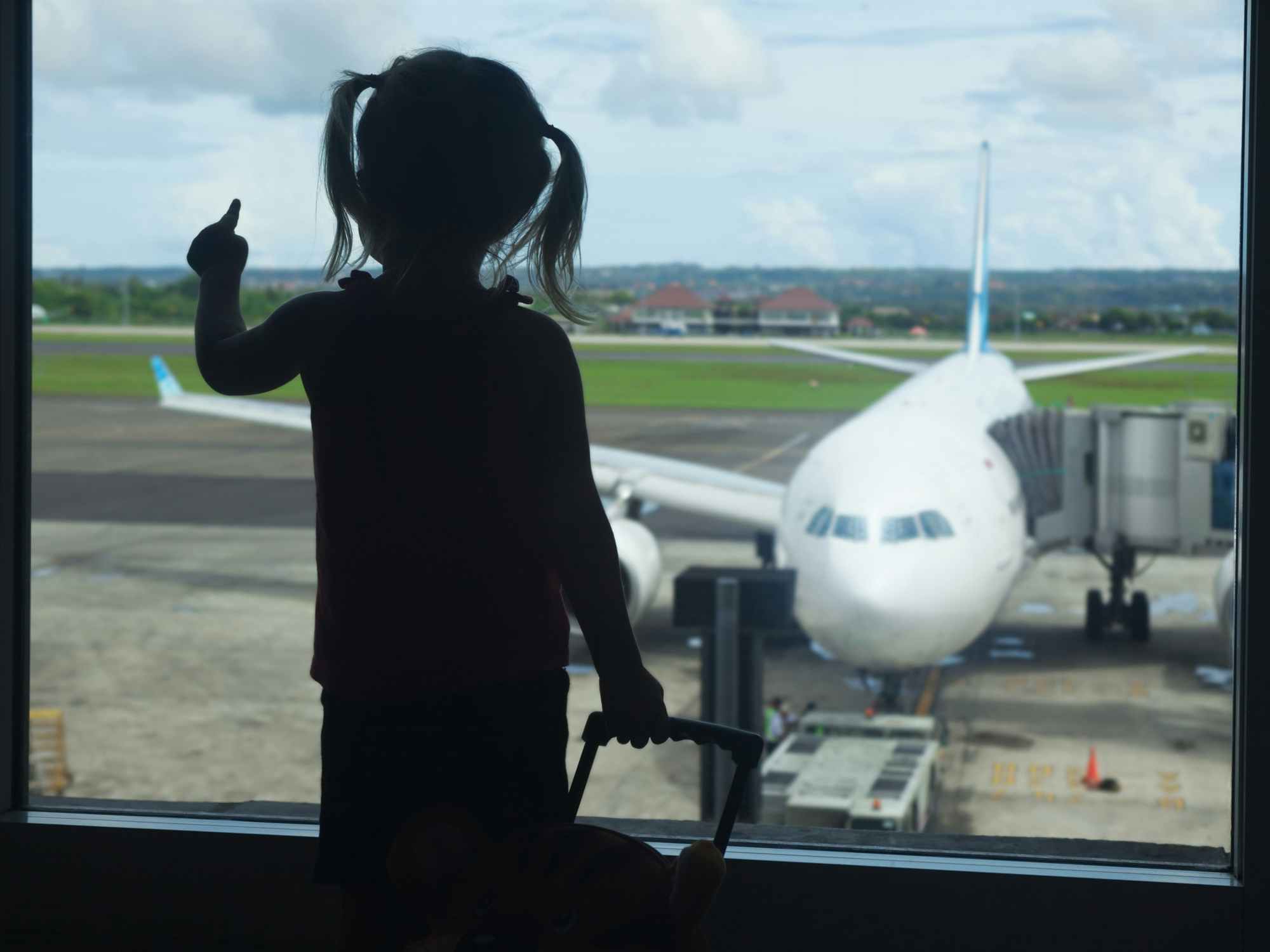 child looking at airplane through a window