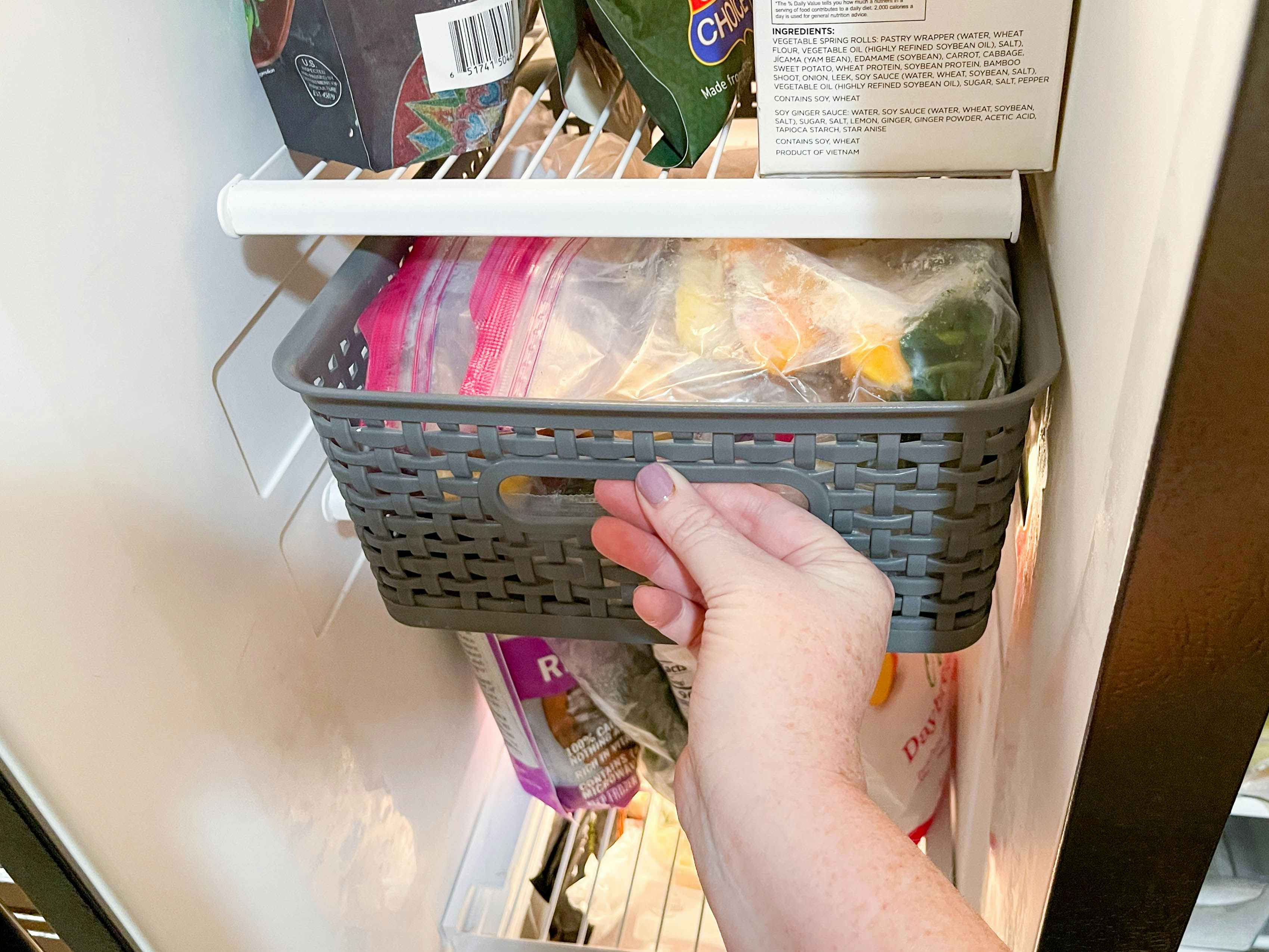 a person pulling a basket out of the freezer 