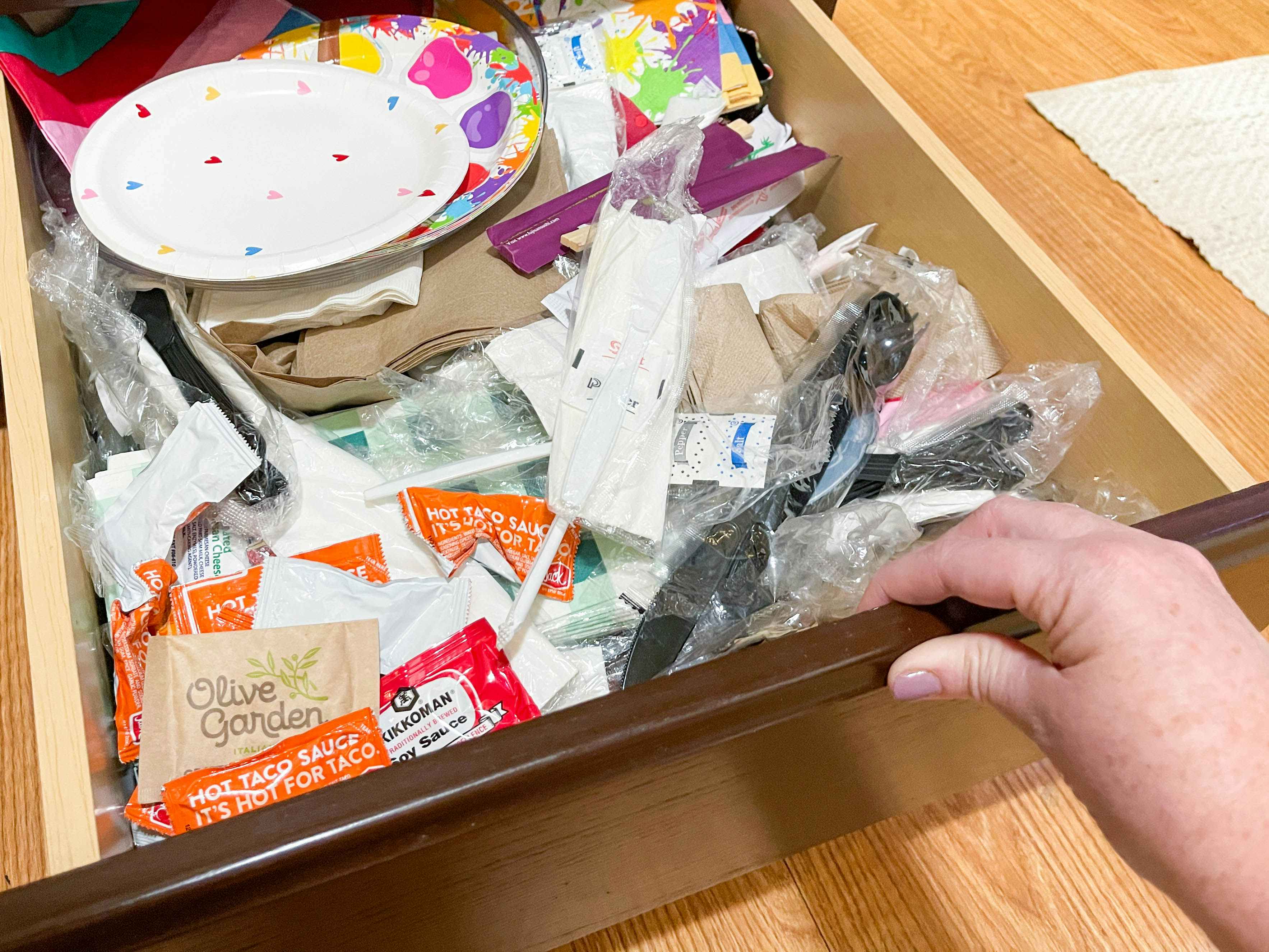 a kitchen drawer filled with paper products, chopsticks, and sauce packets 