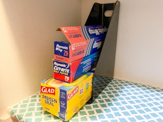 a magazine rack in a pantry with tin foil and wax paper