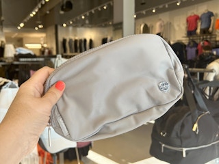 hand holding gray lululemon belt bag in store