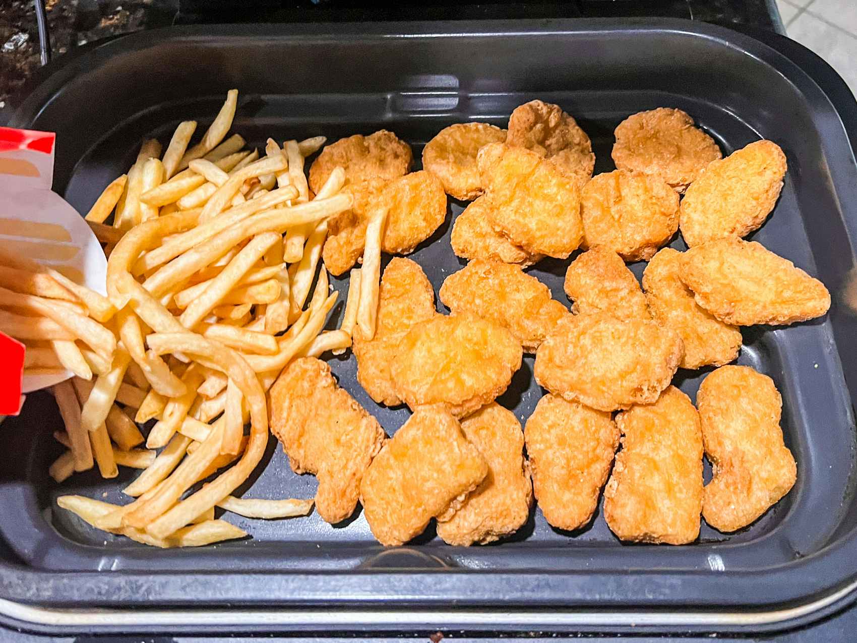 Chicken nuggets and fries inside an air fryer