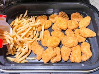 Chicken nuggets and fries inside an air fryer